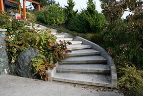 Stairs descend from the Sunning Terrace to the basement entry or into the coastal meadow.